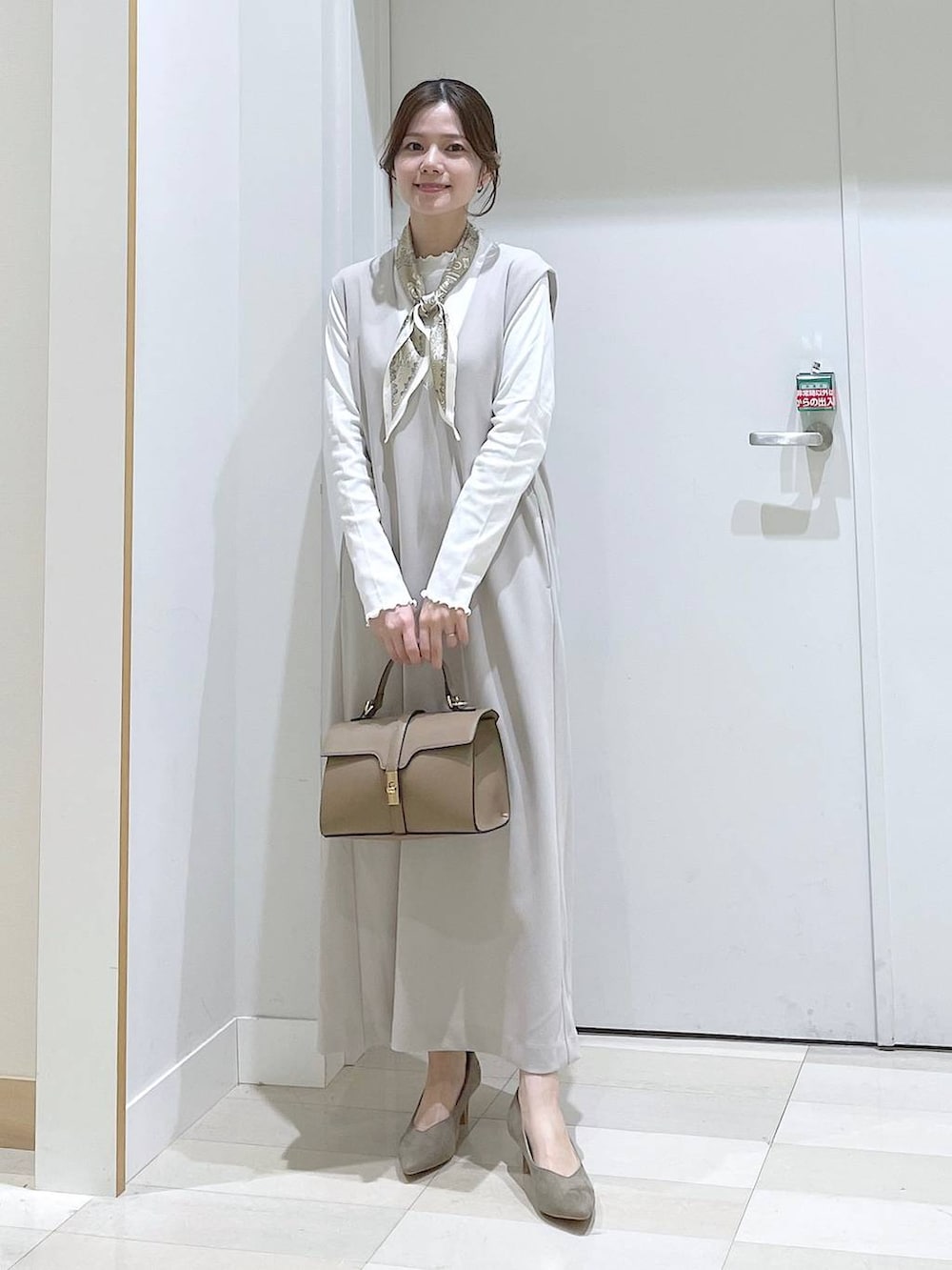 グレー系のジャンパースカート、ベージュ系のショルダーバッグ、ベージュ系のパンプスを着用したレディースの春コーディネートの4枚目の写真