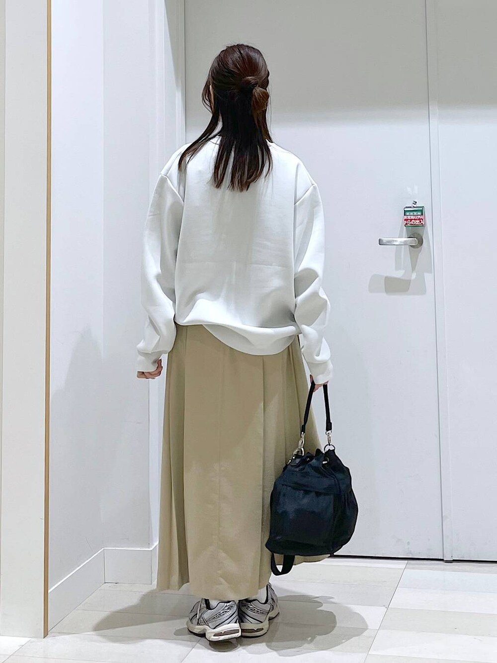 ホワイト系のスウェット、ブラック系のショルダーバッグ、ベージュ系のスカートを着用したレディースの春コーディネートの3枚目の写真