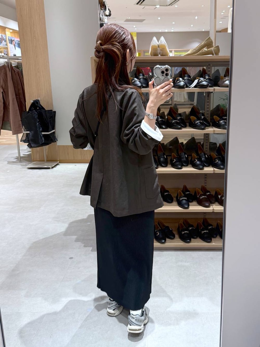 ブラック系のスカート、ブラウン系のテーラードジャケット、ホワイト系のTシャツ/カットソーを着用したレディースの秋コーディネートの3枚目の写真