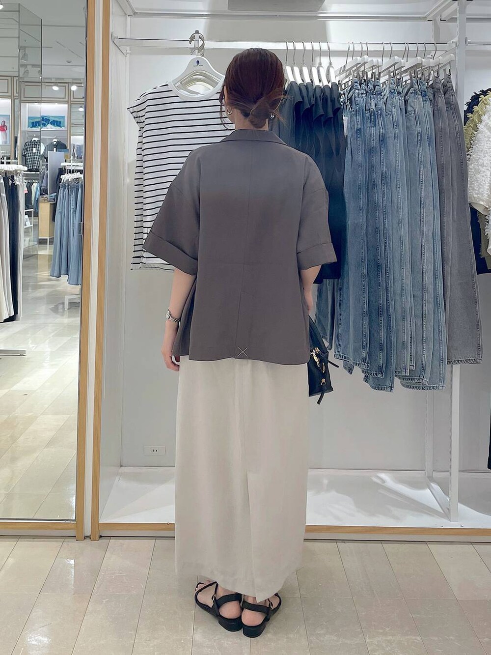 ブラック系のショルダーバッグ、グレー系のスカート、ブラック系のサンダルを着用したレディースの夏コーディネートの3枚目の写真