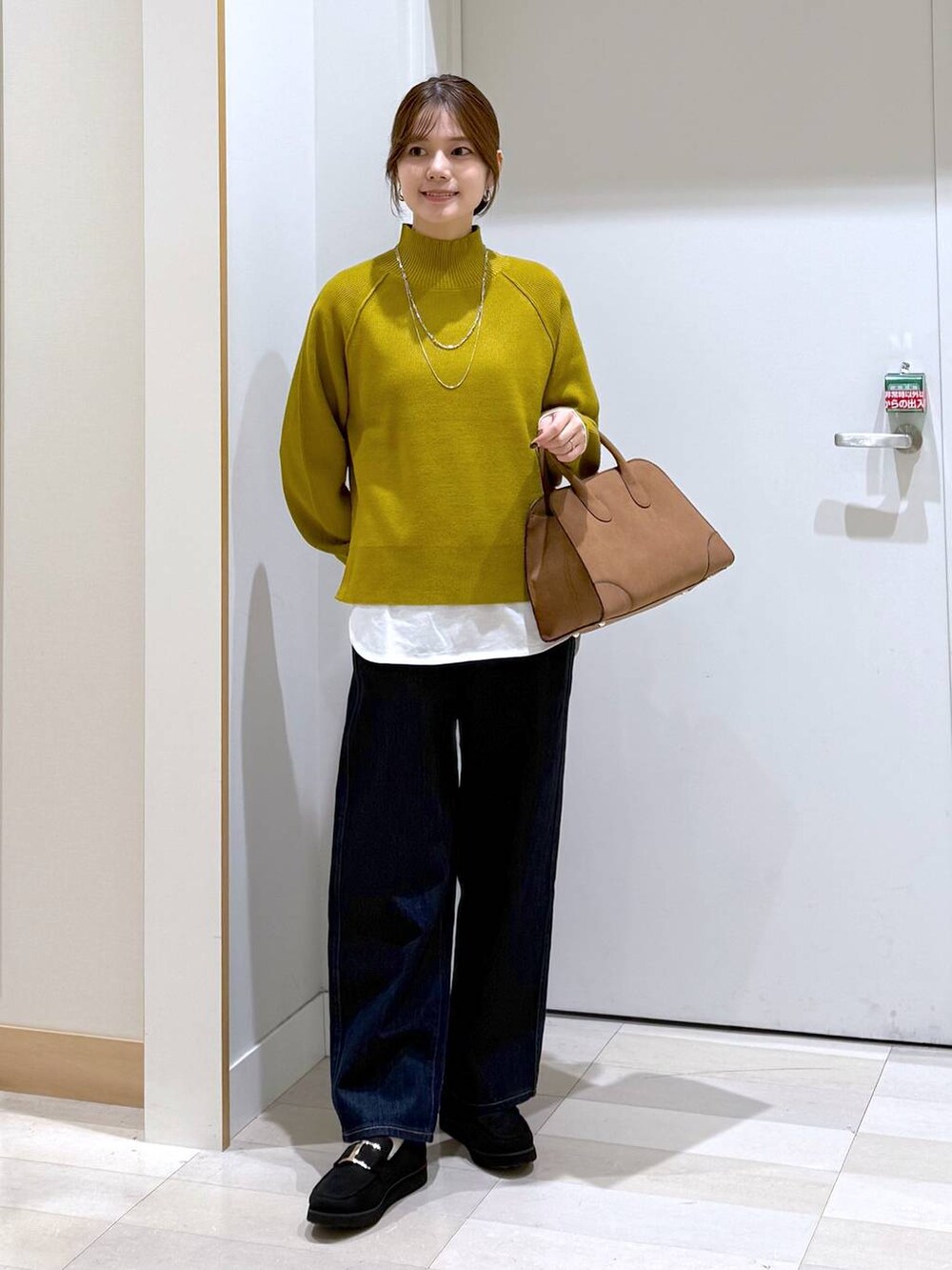 ブラック系のローファー、ブルー系のデニムパンツ、ブラック系のショルダーバッグを着用したレディースの秋コーディネートの4枚目の写真