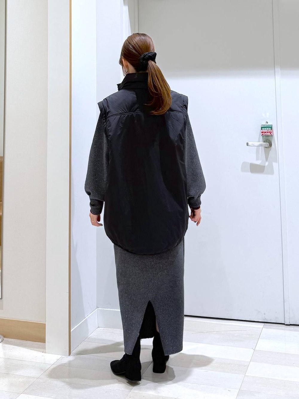 ブラック系のブルゾン、レッド系のニット/セーター、グレー系のワンピースを着用したレディースの秋コーディネートの3枚目の写真