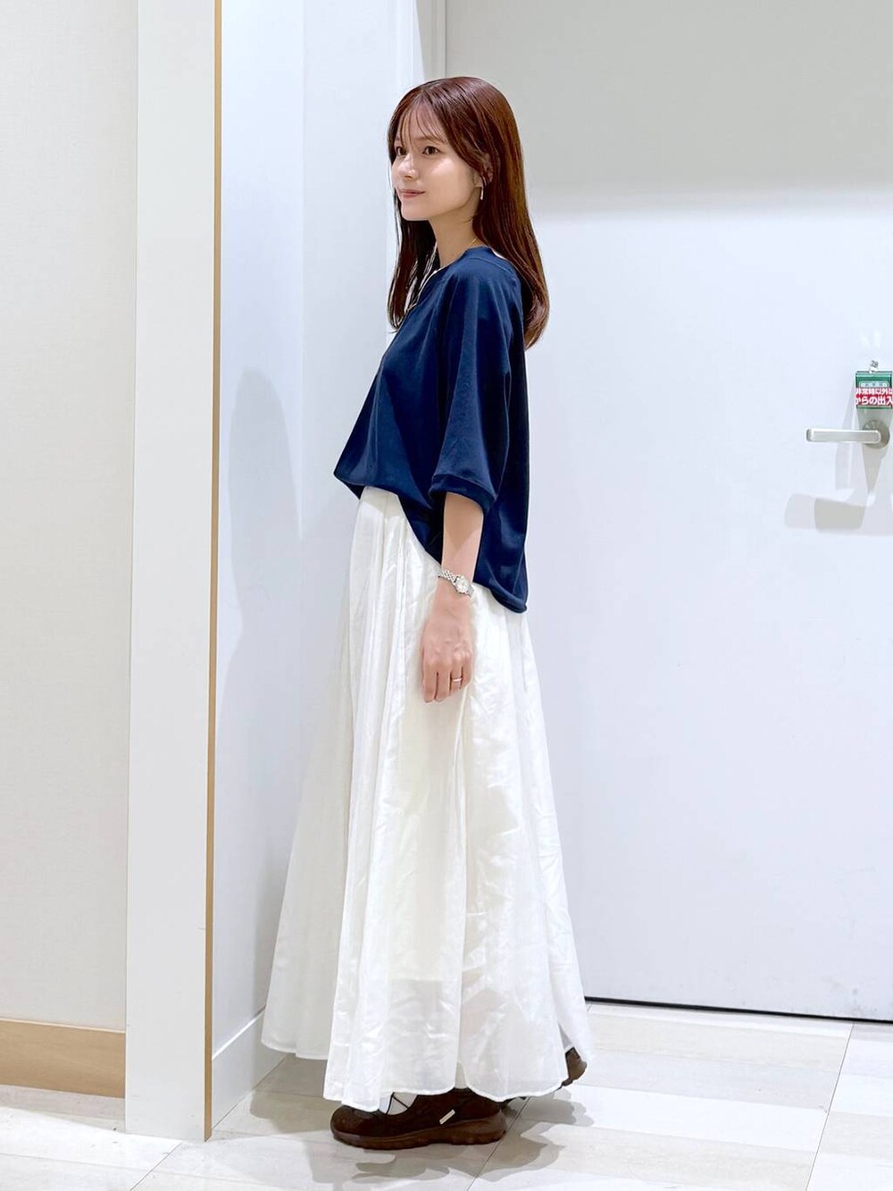 ベージュ系のスカート、ブルー系のTシャツ/カットソー、ゴールド系のネックレスを着用したレディースの秋コーディネートの2枚目の写真