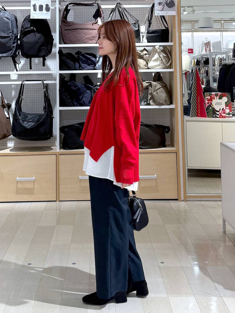 ブラック系のダウンジャケット/コート、レッド系のニット/セーター、ブルー系のその他パンツを着用したレディースの冬コーディネートの2枚目の写真