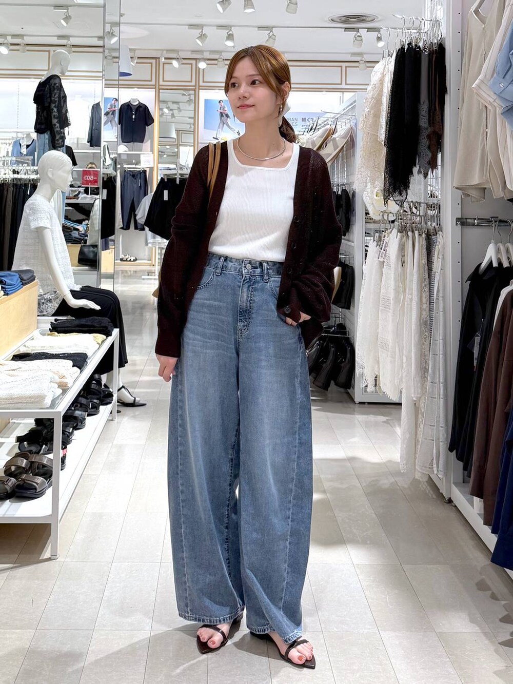 ブラウン系のボストンバッグ、ブルー系のデニムパンツ、ホワイト系のタンクトップを着用したレディースの夏コーディネートの4枚目の写真