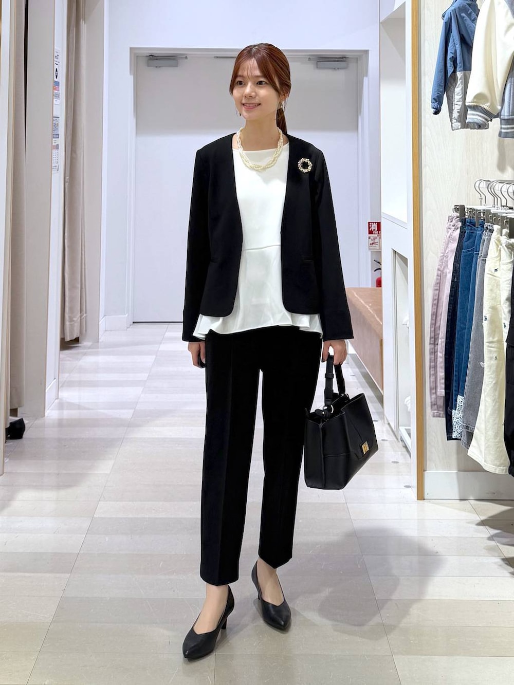 ブラック系のパンプス、ブラック系のセットアップ、ブラック系のショルダーバッグを着用したレディースの冬コーディネートの4枚目の写真
