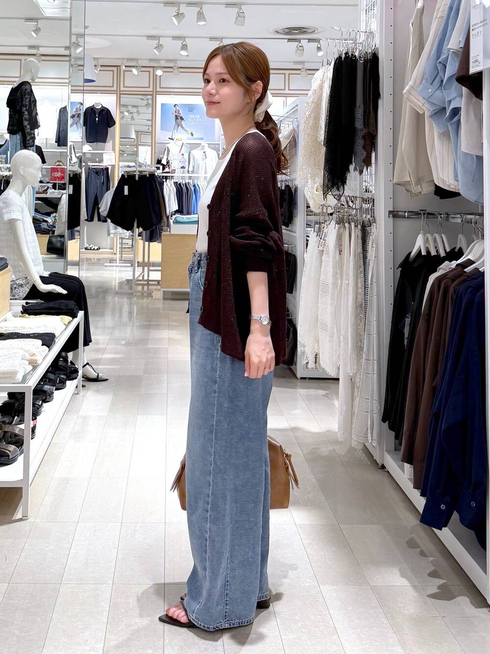 ブラウン系のボストンバッグ、ブルー系のデニムパンツ、ホワイト系のタンクトップを着用したレディースの夏コーディネートの2枚目の写真