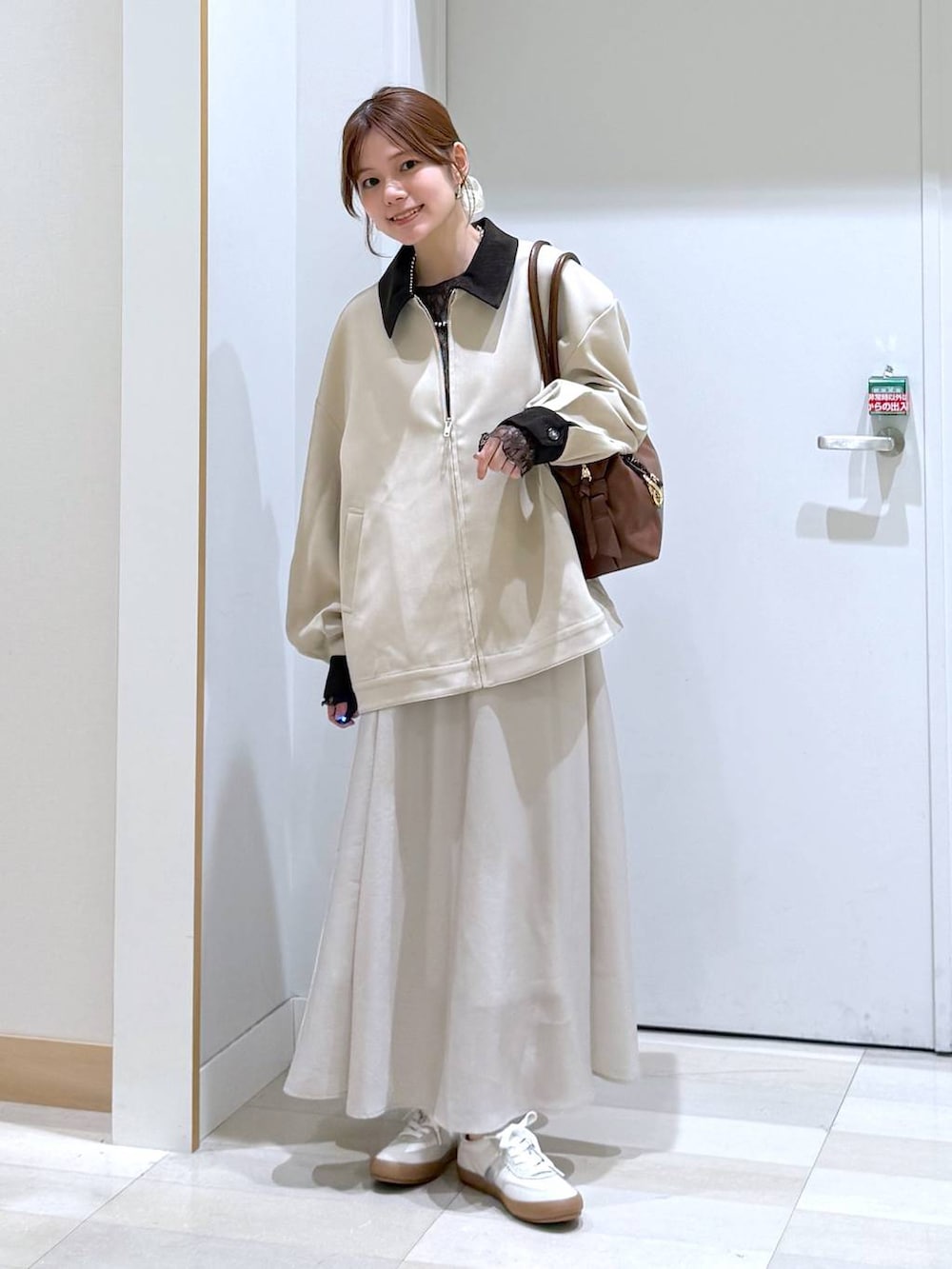 ホワイト系のスニーカー、ブラウン系のボストンバッグ、ベージュ系のスカートを着用したレディースの春コーディネートの4枚目の写真