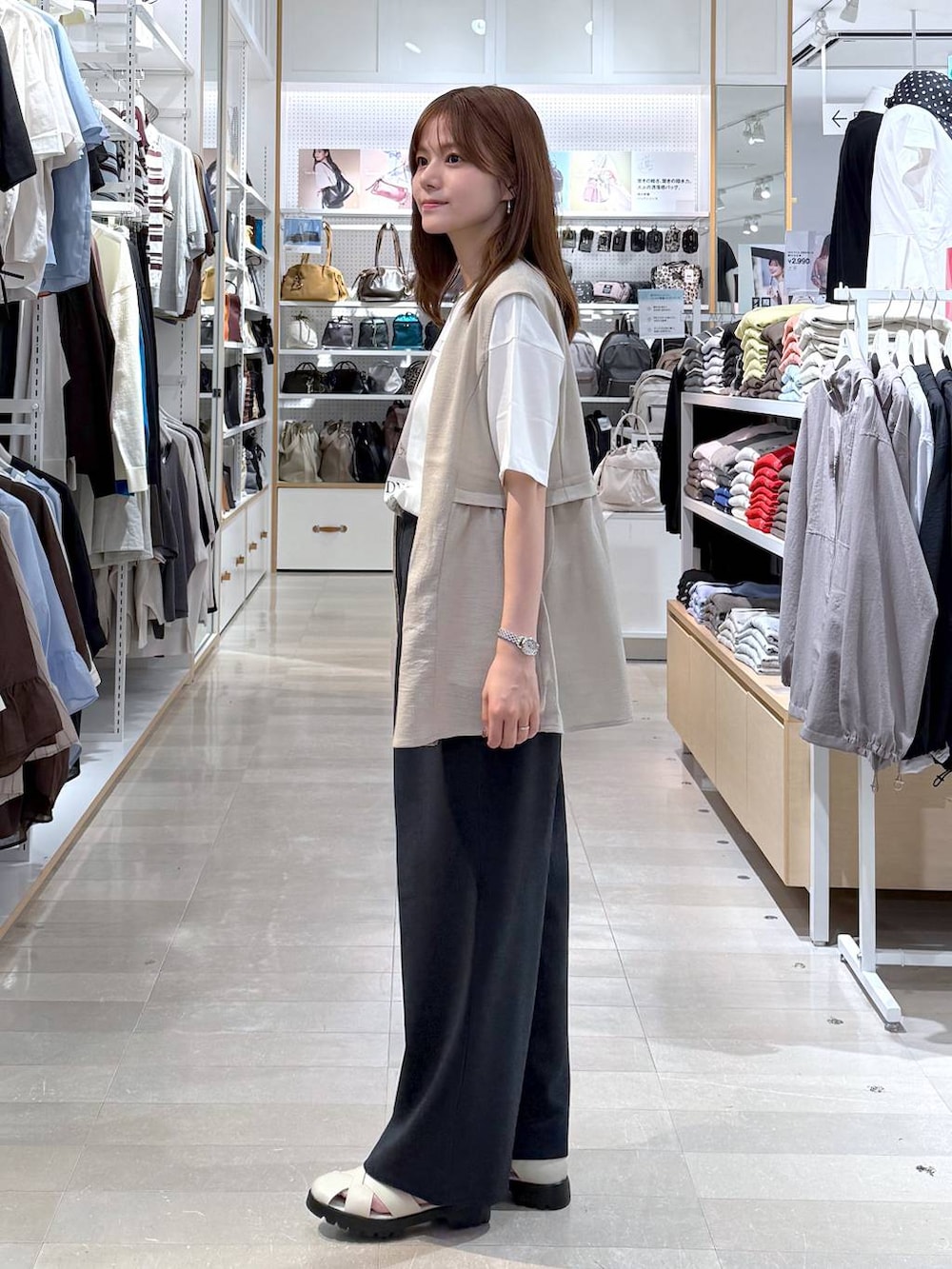 ベージュ系のショルダーバッグ、ベージュ系のベスト、ホワイト系のTシャツ/カットソーを着用したレディースの春コーディネートの2枚目の写真