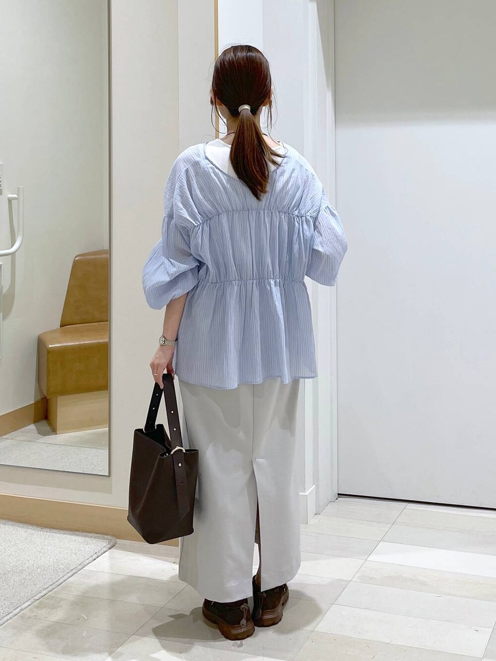 ブラウン系のショルダーバッグ、グレー系のスカート、ブルー系のシャツ/ブラウスを着用したレディースの夏コーディネートの3枚目の写真