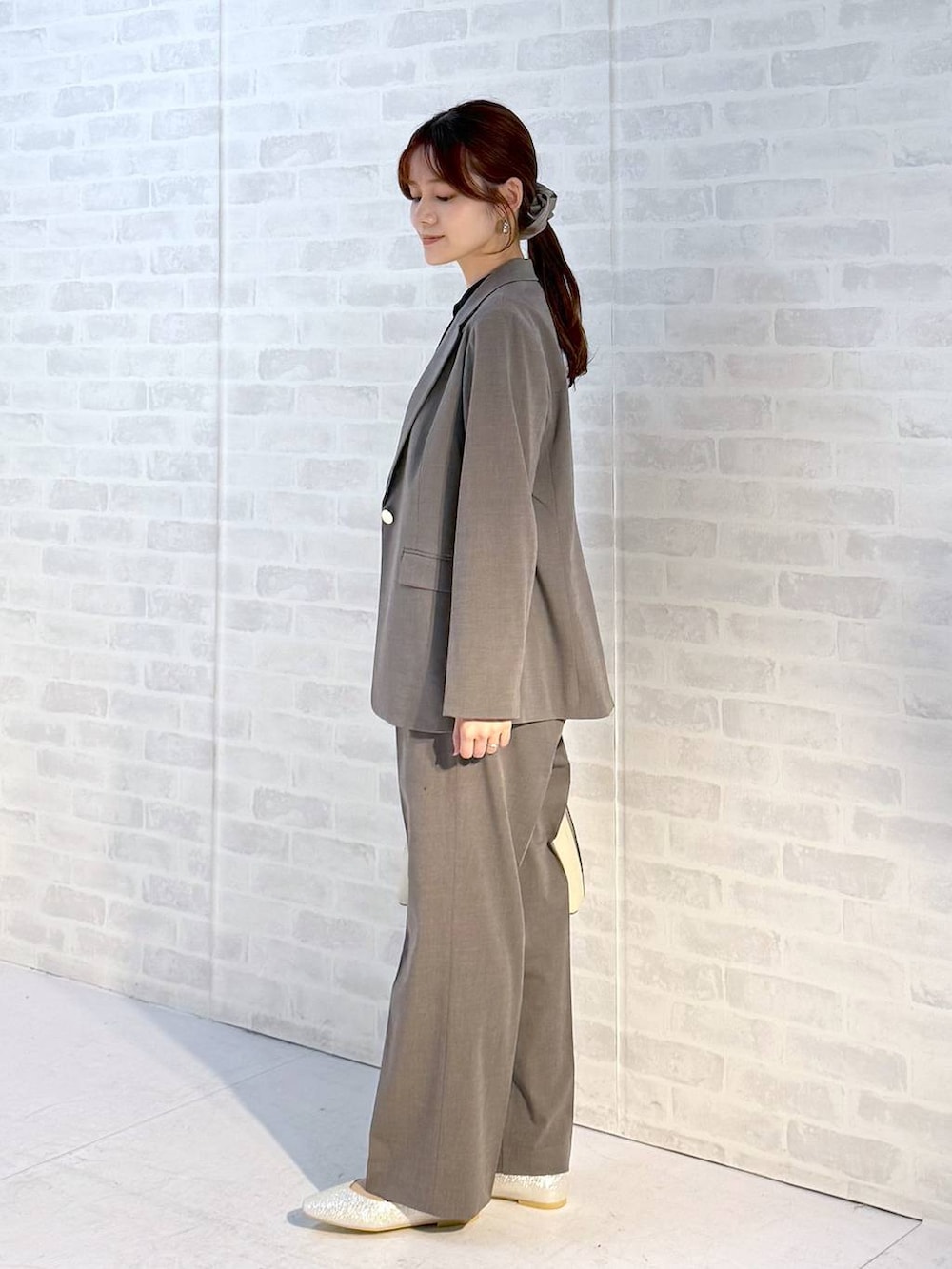 ベージュ系のパンプス、ホワイト系のショルダーバッグ、ブラウン系のスラックスを着用したレディースの冬コーディネートの2枚目の写真