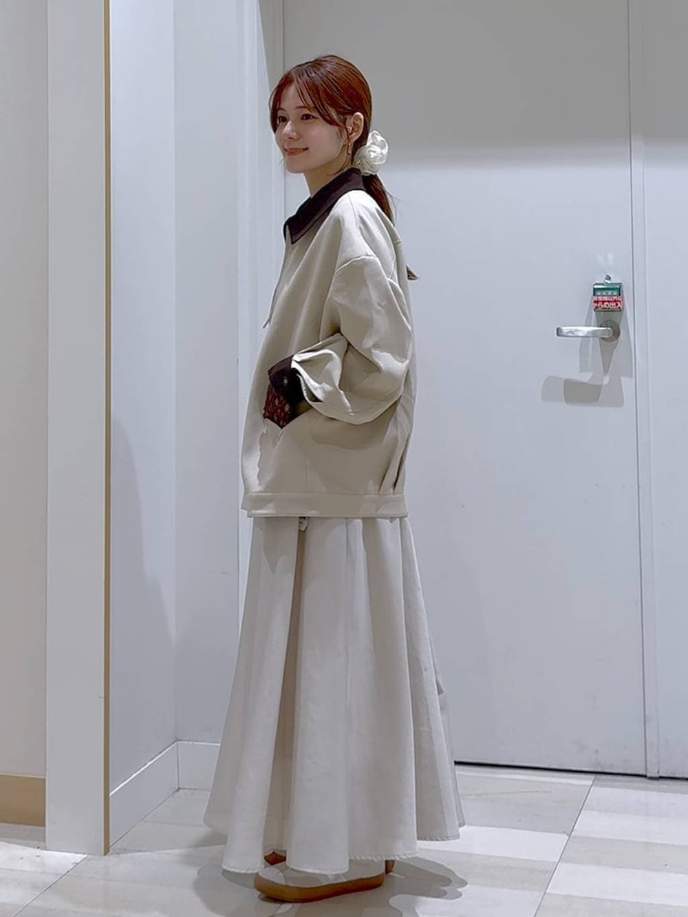 ホワイト系のスニーカー、ブラウン系のボストンバッグ、ベージュ系のスカートを着用したレディースの春コーディネートの2枚目の写真