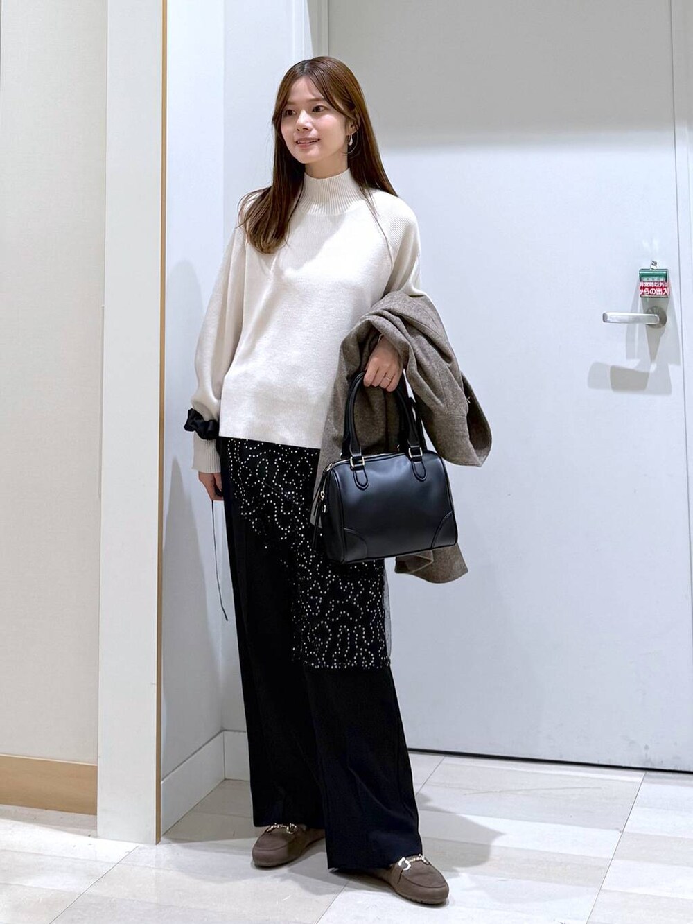 ブラウン系のチェスターコート、ブラック系のその他パンツ、ホワイト系のニット/セーターを着用したレディースの秋コーディネートの5枚目の写真
