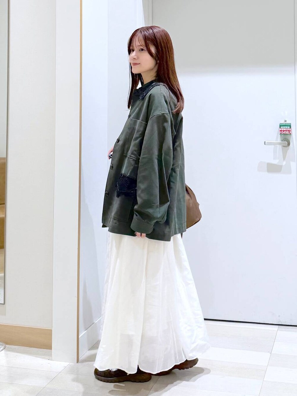 ブラウン系のショルダーバッグ、ベージュ系のスカート、ブルー系のTシャツ/カットソーを着用したレディースの秋コーディネートの2枚目の写真