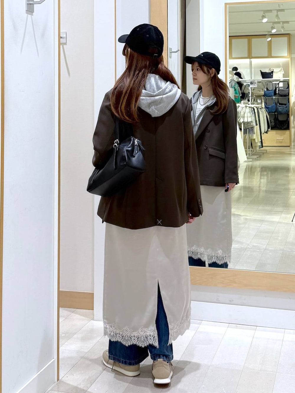 ブルー系のデニムパンツ、ベージュ系のスニーカー、ブラウン系のテーラードジャケットを着用したレディースの冬コーディネートの3枚目の写真