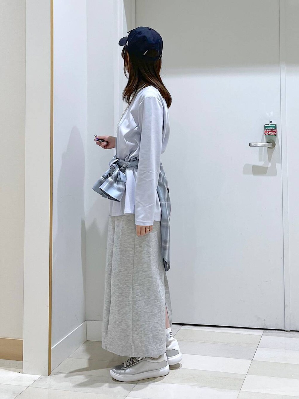 シルバー系のスニーカー、ブラック系のショルダーバッグ、ブルー系のシャツ/ブラウスを着用したレディースの春コーディネートの2枚目の写真