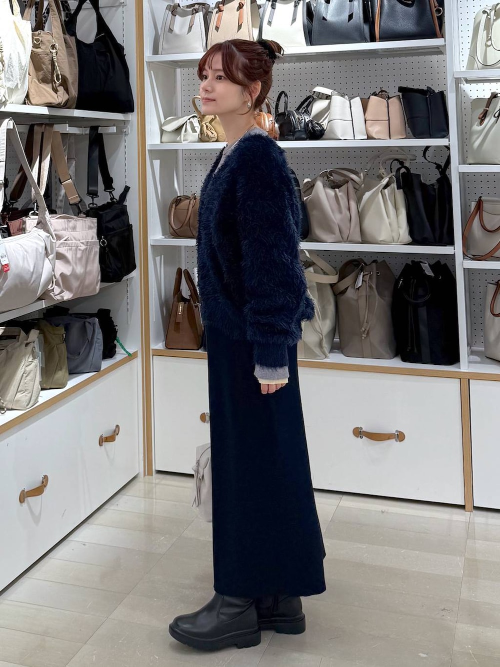 ブラック系のダウンジャケット/コート、ホワイト系のボストンバッグ、ブルー系のワンピースを着用したレディースの冬コーディネートの2枚目の写真