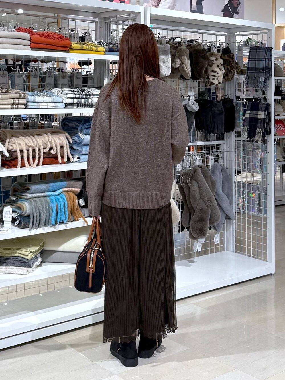 ブラウン系のワンピース、ブラック系のボストンバッグ、ブラック系のブーツを着用したレディースの冬コーディネートの3枚目の写真