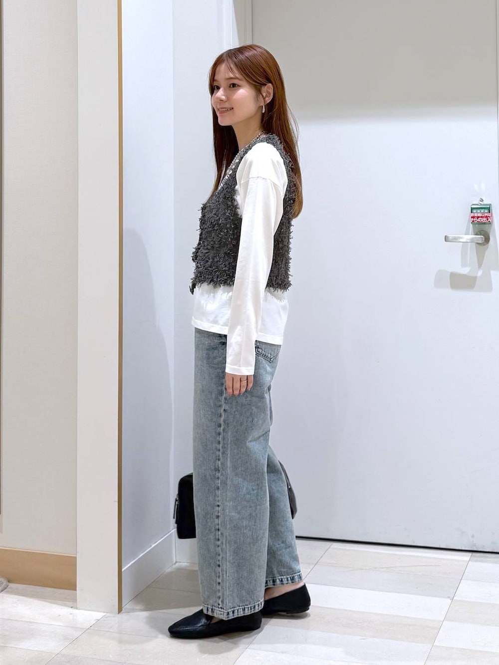 ブラック系のその他シューズ、ブルー系のデニムパンツ、ブラック系のショルダーバッグを着用したレディースの春コーディネートの2枚目の写真