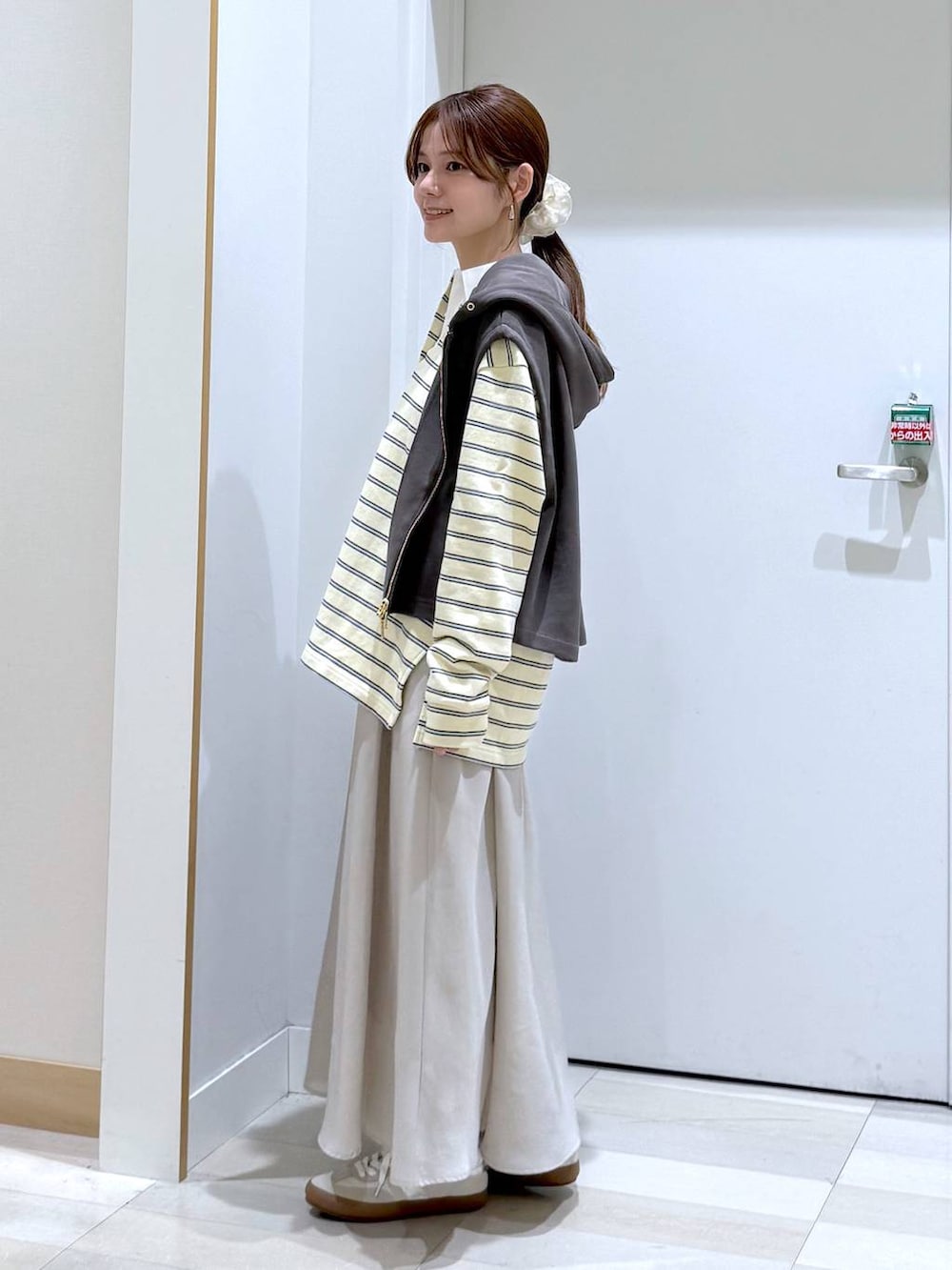 ホワイト系のスニーカー、ブラック系のハンドバッグ、ベージュ系のスカートを着用したレディースの春コーディネートの2枚目の写真