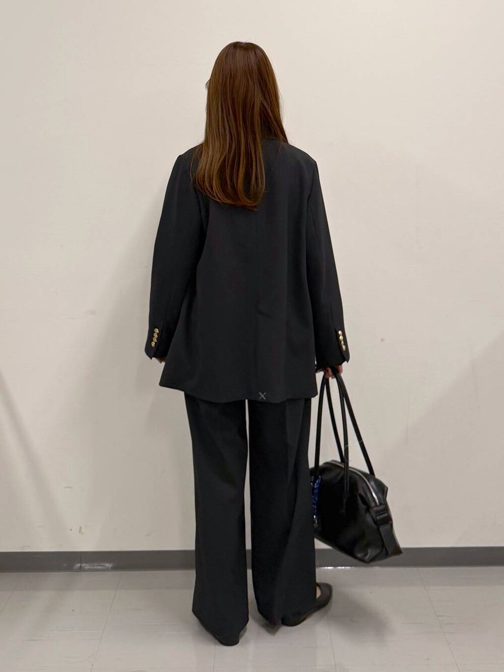 ブラック系のパンプス、ブラック系のボストンバッグ、ブルー系のテーラードジャケットを着用したレディースの冬コーディネートの3枚目の写真