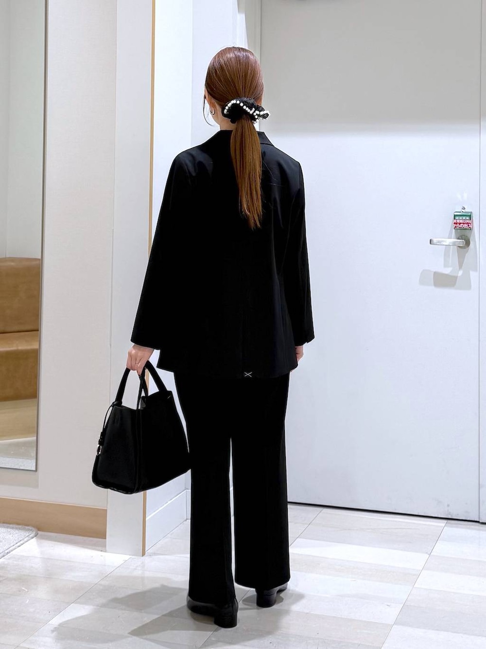 ブラック系のパンプス、ブラック系のトートバッグ、ブラック系のスラックスを着用したレディースの春コーディネートの4枚目の写真
