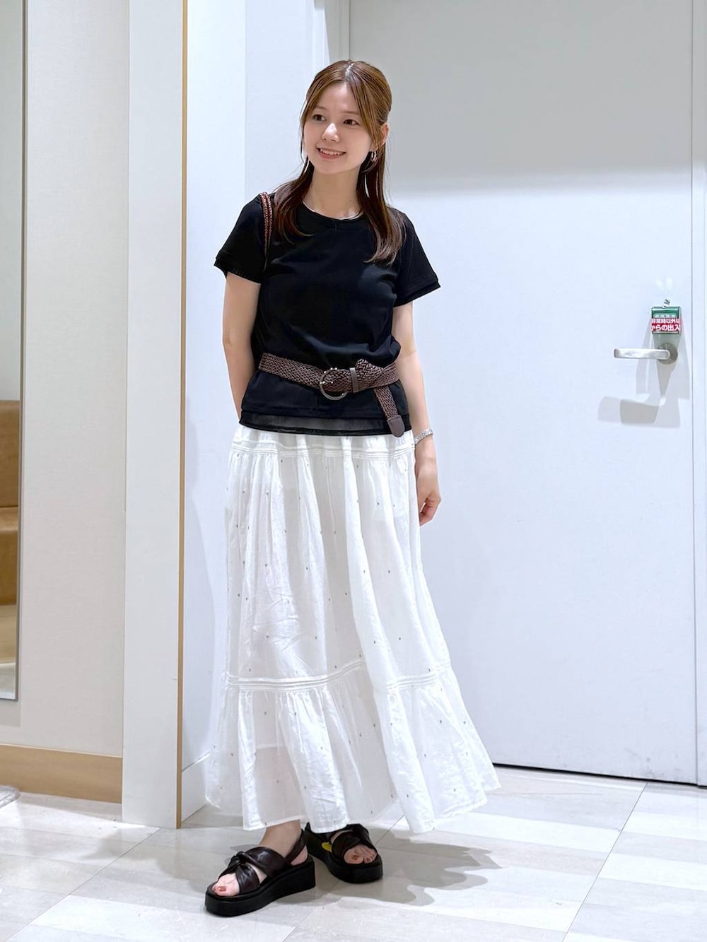 ホワイト系のスカート、ブラウン系のクラッチバッグ、ブラック系のTシャツ/カットソーを着用したレディースの夏コーディネートの4枚目の写真