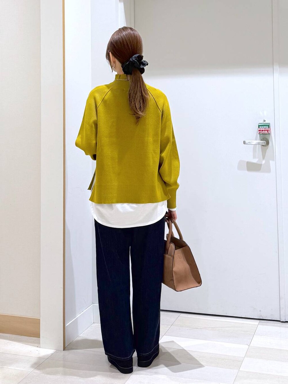 ブラック系のローファー、ブルー系のデニムパンツ、ブラック系のショルダーバッグを着用したレディースの秋コーディネートの3枚目の写真