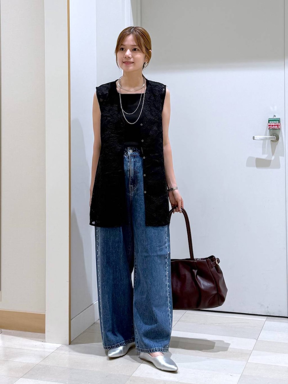 ブルー系のデニムパンツ、レッド系のボストンバッグ、ブラック系のベストを着用したレディースの夏コーディネートの4枚目の写真