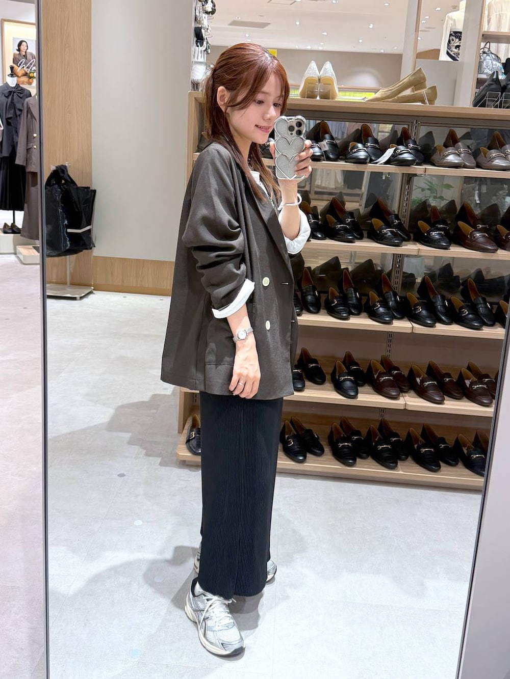 ブラック系のスカート、ブラウン系のテーラードジャケット、ホワイト系のTシャツ/カットソーを着用したレディースの秋コーディネートの2枚目の写真