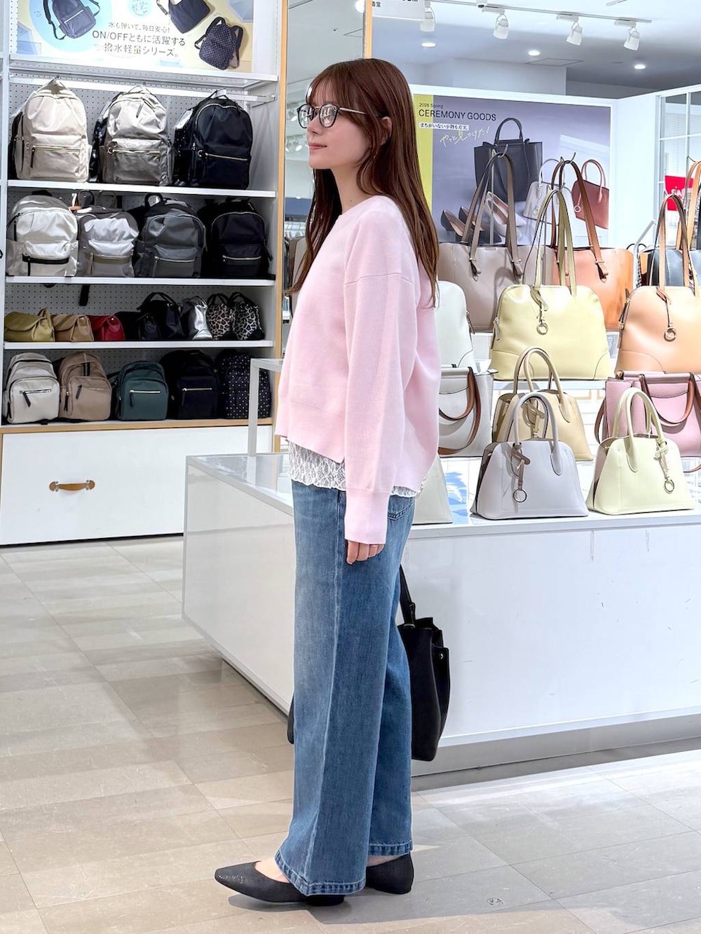 ブラック系のパンプス、ブルー系のデニムパンツ、ピンク系のニット/セーターを着用したレディースの春コーディネートの2枚目の写真