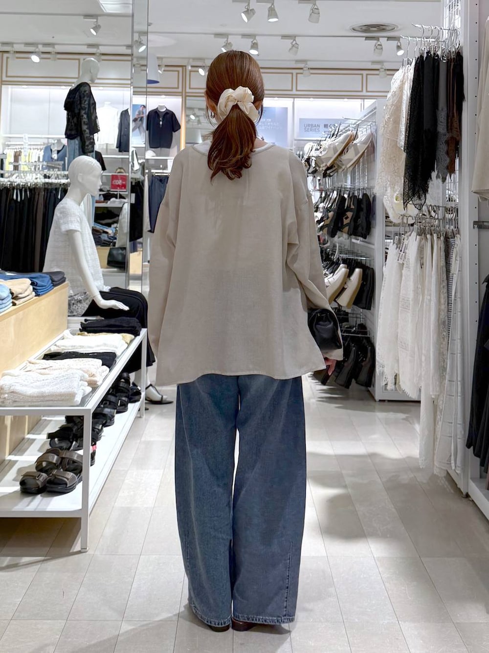 ブラック系のショルダーバッグ、ブルー系のデニムパンツ、ホワイト系のタンクトップを着用したレディースの夏コーディネートの3枚目の写真