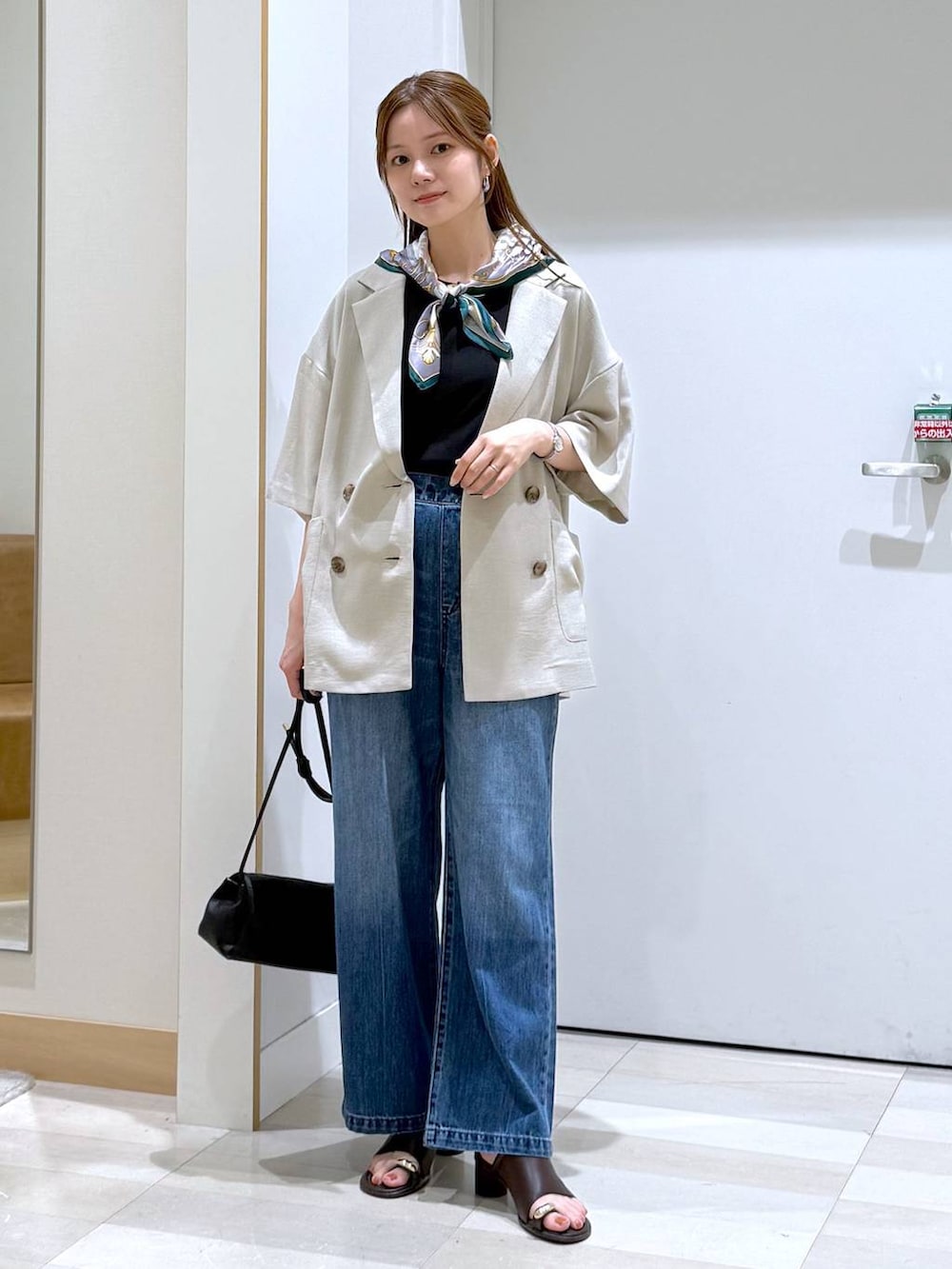 ブルー系のデニムパンツ、ブラック系のショルダーバッグ、ベージュ系のテーラードジャケットを着用したレディースの夏コーディネートの4枚目の写真