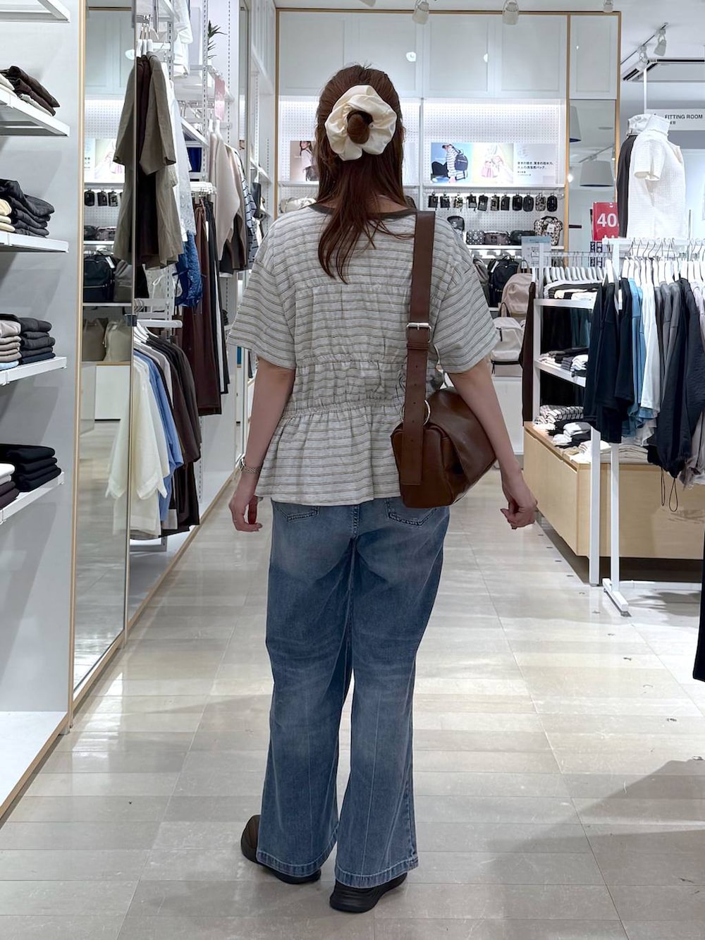 ブルー系のデニムパンツ、ブラウン系のスニーカー、ホワイト系のTシャツ/カットソーを着用したレディースの夏コーディネートの3枚目の写真