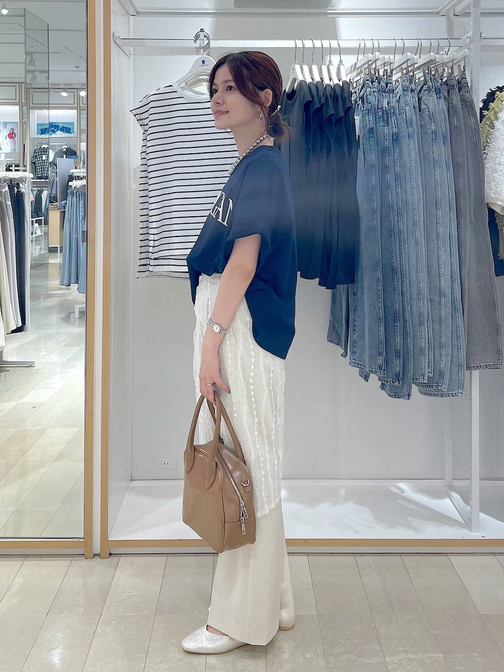 ベージュ系のパンプス、ベージュ系のボストンバッグ、ブルー系のTシャツ/カットソーを着用したレディースの夏コーディネートの2枚目の写真
