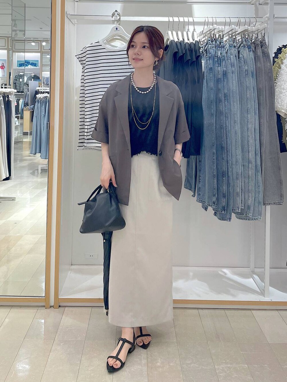 ブラック系のショルダーバッグ、グレー系のスカート、ブラック系のサンダルを着用したレディースの夏コーディネートの4枚目の写真