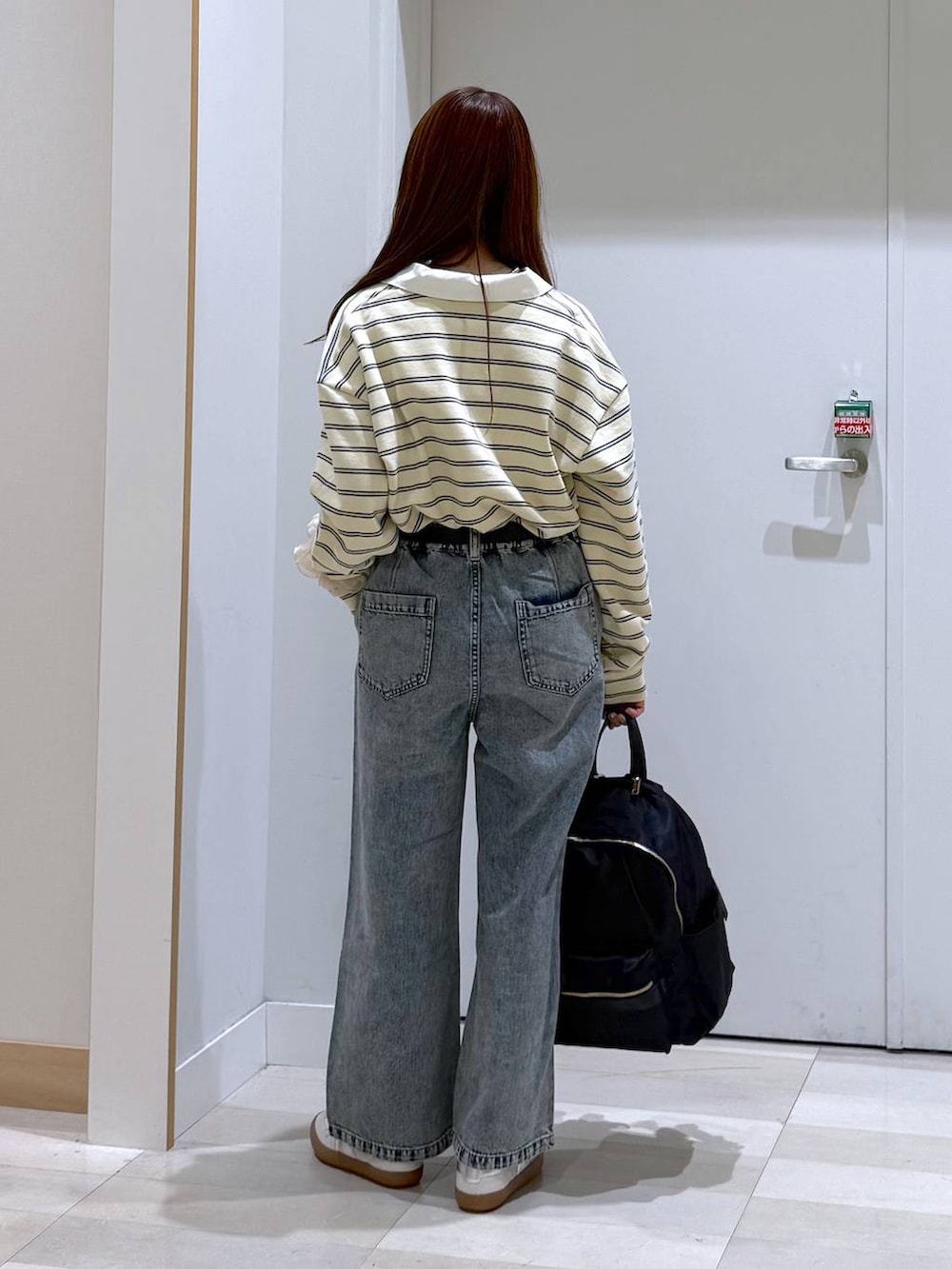 ホワイト系のスニーカー、ブラック系のバックパック/リュック、ブルー系のデニムパンツを着用したレディースの春コーディネートの4枚目の写真