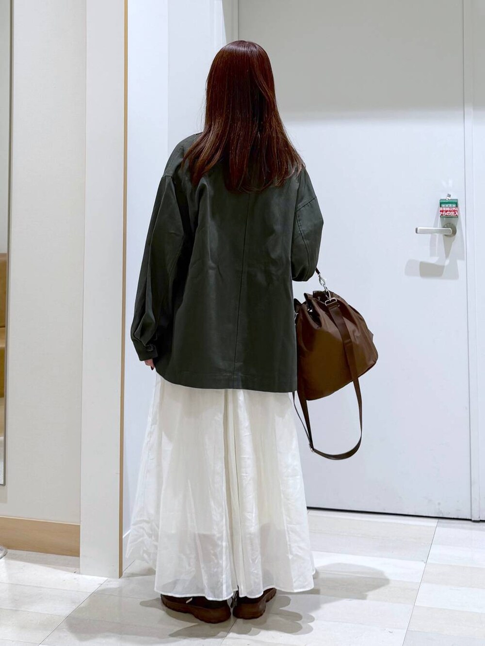 ブラウン系のショルダーバッグ、ベージュ系のスカート、ブルー系のTシャツ/カットソーを着用したレディースの秋コーディネートの3枚目の写真