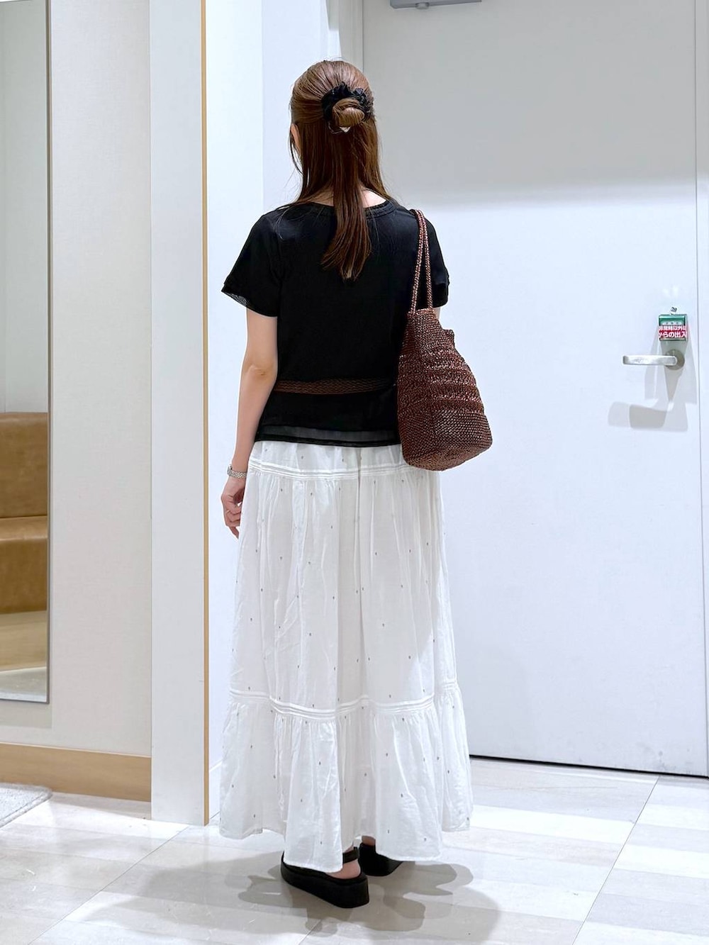 ホワイト系のスカート、ブラウン系のクラッチバッグ、ブラック系のTシャツ/カットソーを着用したレディースの夏コーディネートの3枚目の写真