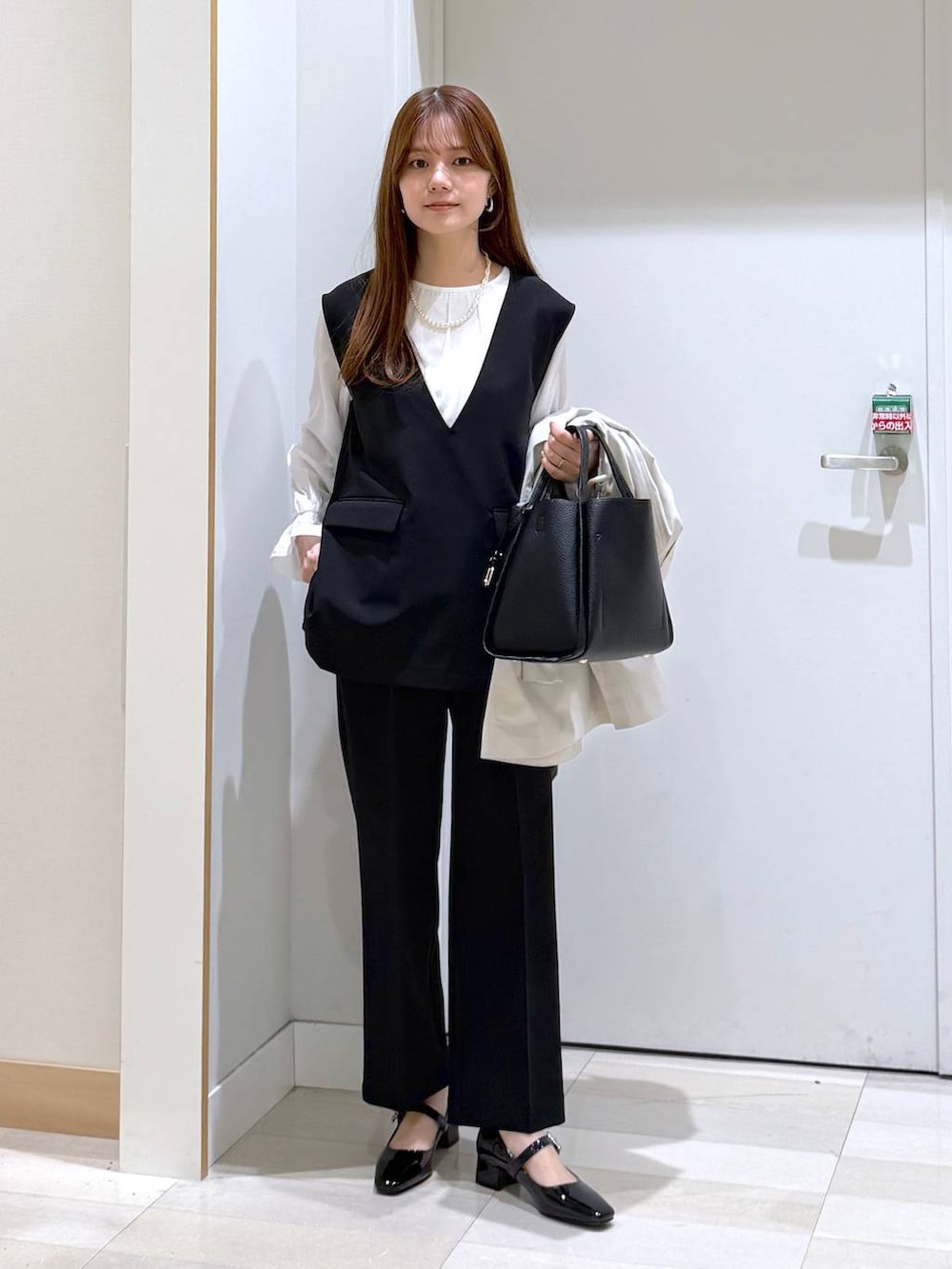 ブラック系のトートバッグ、ブラック系のセットアップ、ベージュ系のトレンチコートを着用したレディースの冬コーディネートの5枚目の写真