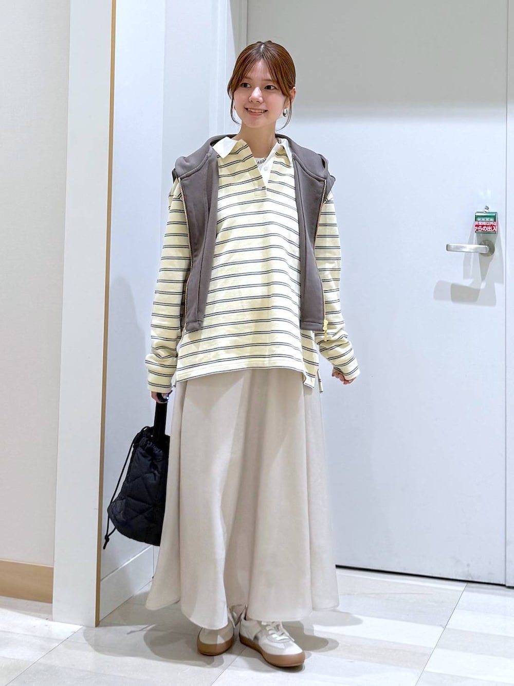 ホワイト系のスニーカー、ブラック系のハンドバッグ、ベージュ系のスカートを着用したレディースの春コーディネートの4枚目の写真