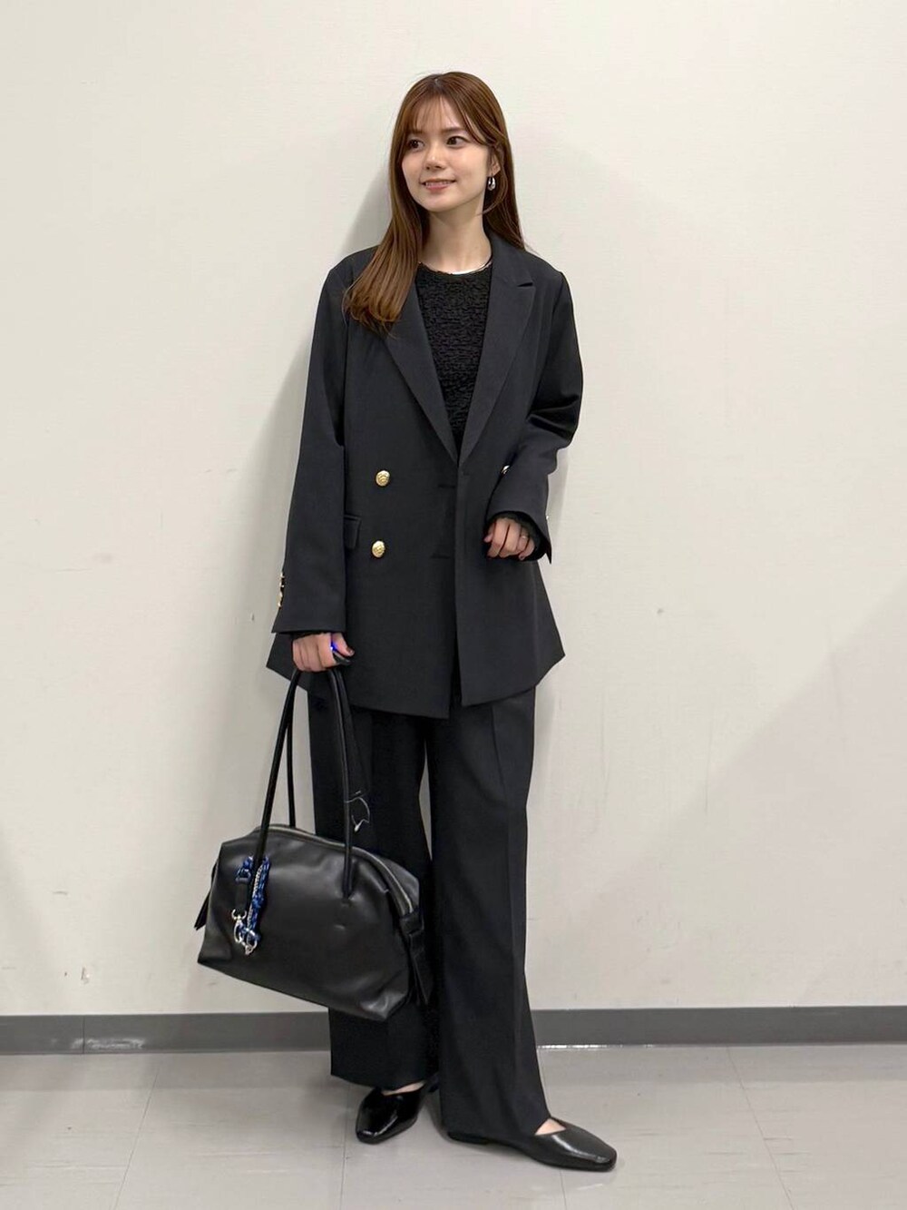 ブラック系のパンプス、ブラック系のボストンバッグ、ブルー系のテーラードジャケットを着用したレディースの冬コーディネートの4枚目の写真