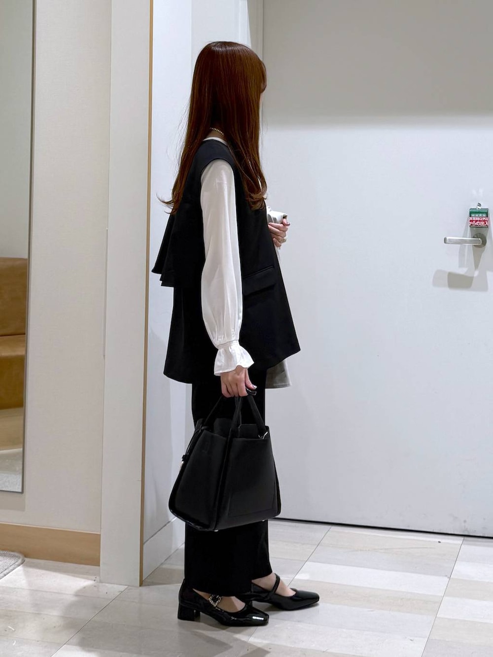 ブラック系のトートバッグ、ブラック系のセットアップ、ベージュ系のトレンチコートを着用したレディースの冬コーディネートの2枚目の写真