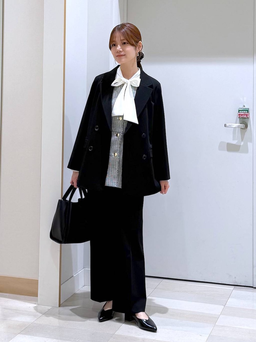 ブラック系のパンプス、ブラック系のトートバッグ、ブラック系のスラックスを着用したレディースの春コーディネートの2枚目の写真