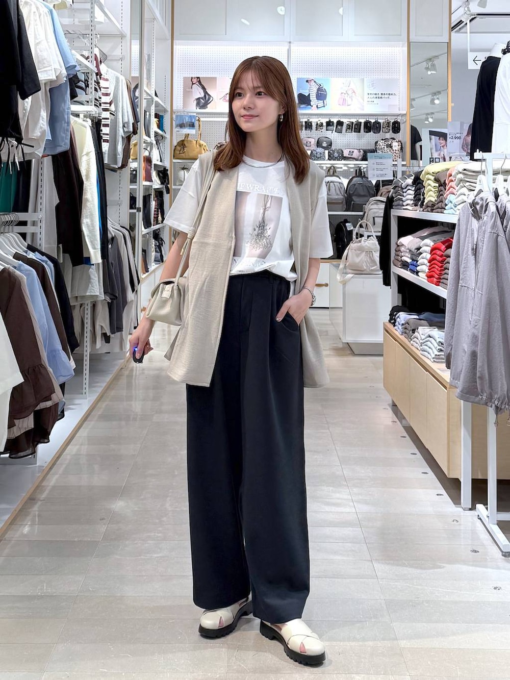 ベージュ系のショルダーバッグ、ベージュ系のベスト、ホワイト系のTシャツ/カットソーを着用したレディースの春コーディネートの4枚目の写真