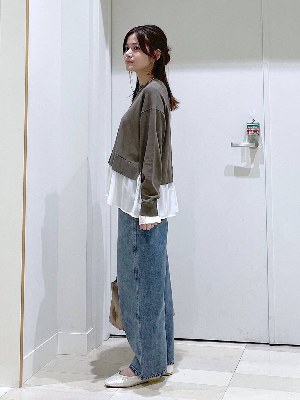 ブルー系のデニムパンツ、ブラウン系のニット/セーター、グレー系のパンプスを着用したレディースの春コーディネートの2枚目の写真