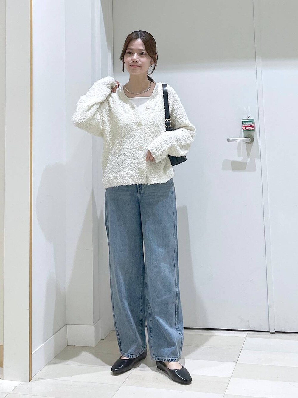 ブルー系のデニムパンツ、ブラック系のパンプス、ブラック系のショルダーバッグを着用したレディースの春コーディネートの4枚目の写真