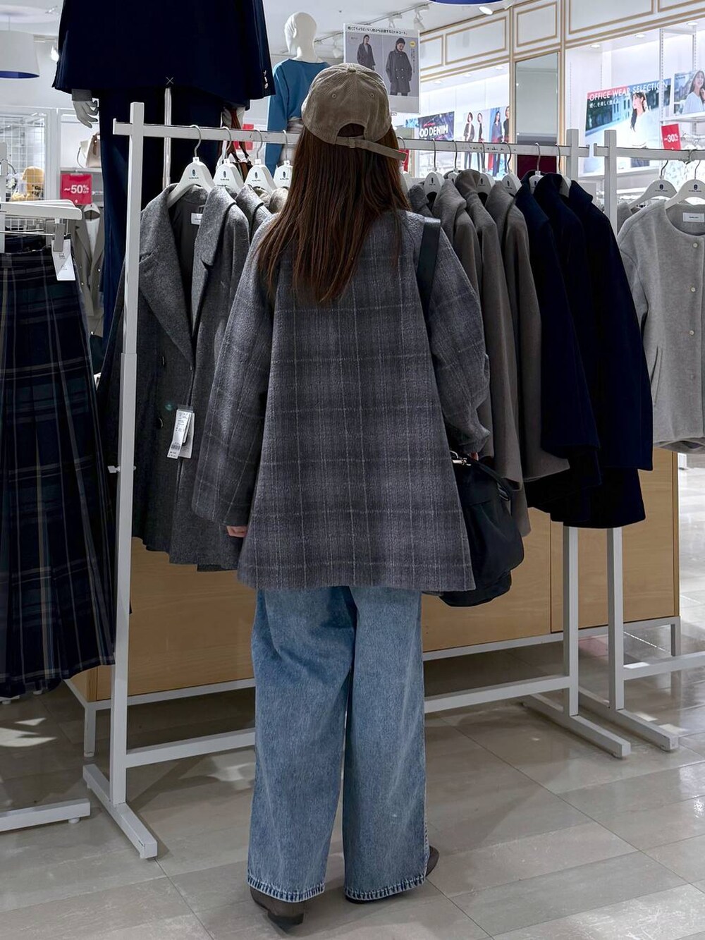 ベージュ系のローファー、ブラック系のショルダーバッグ、ブルー系のデニムパンツを着用したレディースの秋コーディネートの3枚目の写真