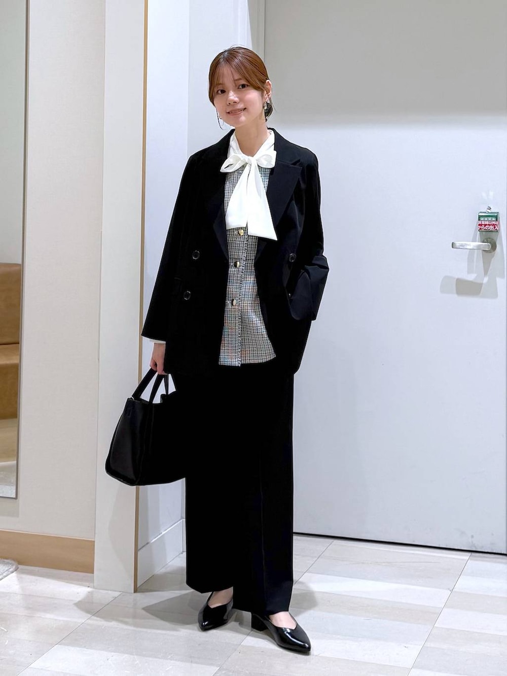 ブラック系のパンプス、ブラック系のトートバッグ、ブラック系のスラックスを着用したレディースの春コーディネートの6枚目の写真