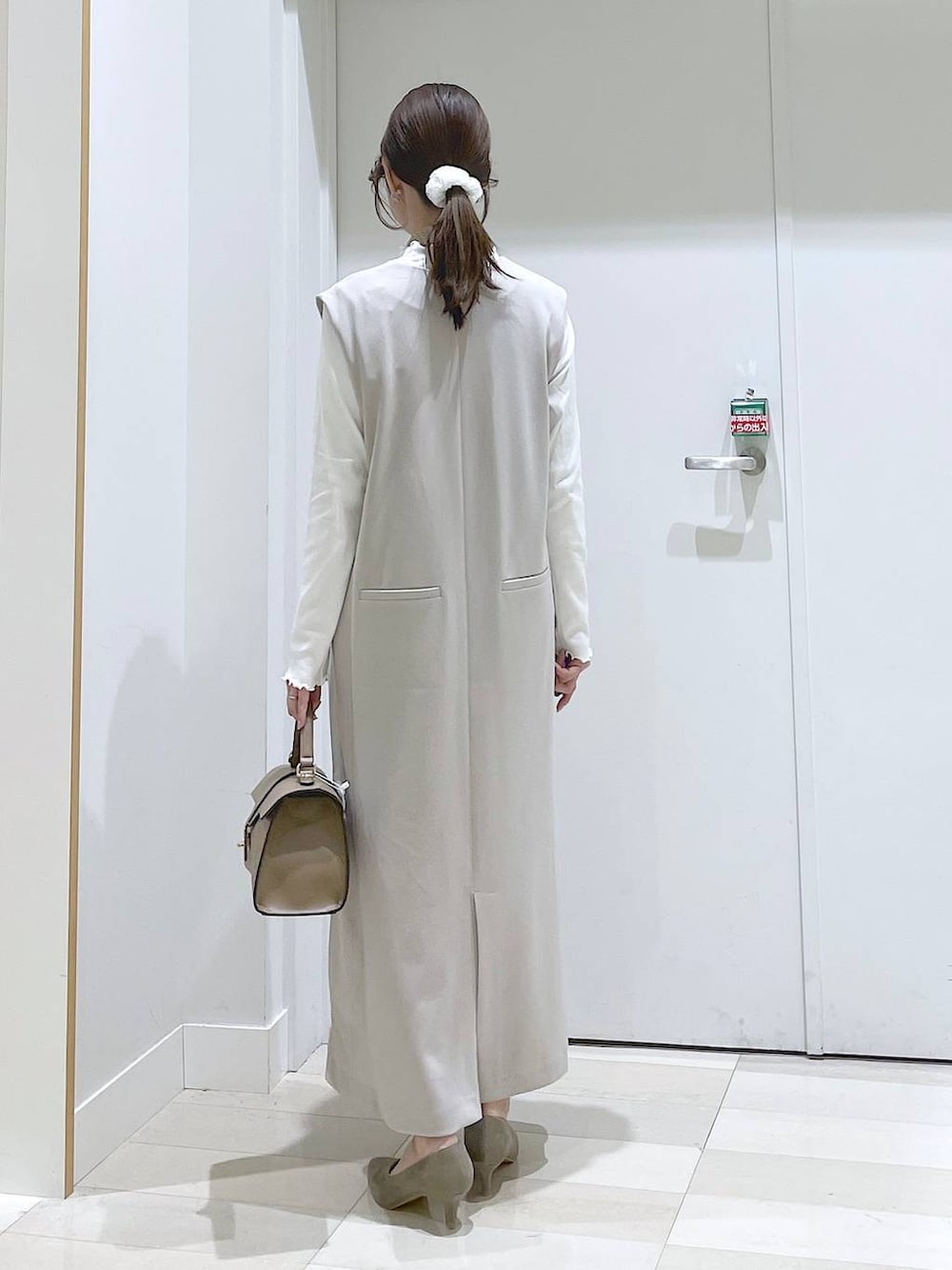 グレー系のジャンパースカート、ベージュ系のショルダーバッグ、ベージュ系のパンプスを着用したレディースの春コーディネートの3枚目の写真